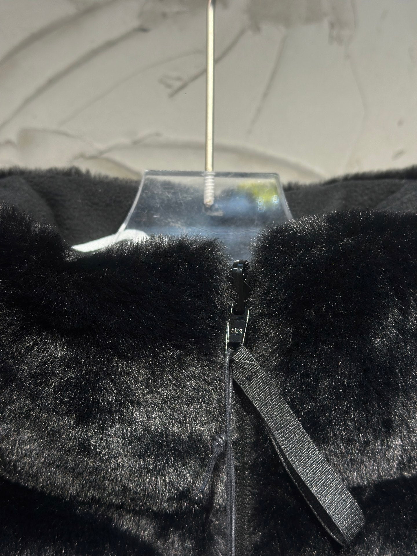 Black faux-fur puffer vest front detail with zipper tape and side strap.
