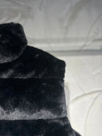 Black faux-fur puffer vest shoulder and upper chest texture view.