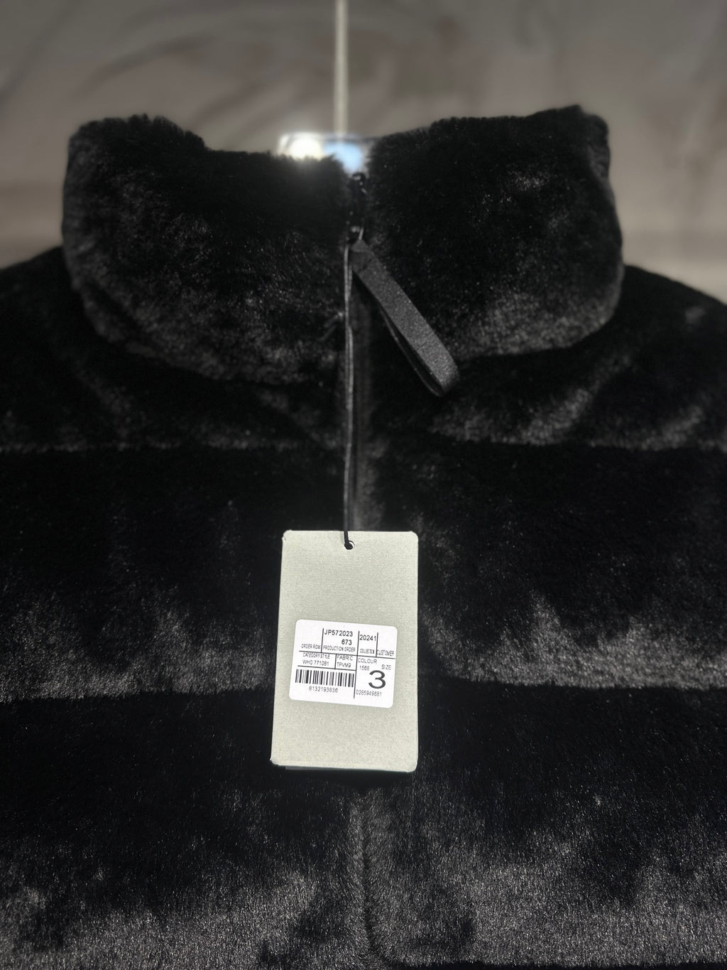 Black faux-fur puffer vest with front zipper and hanging label.