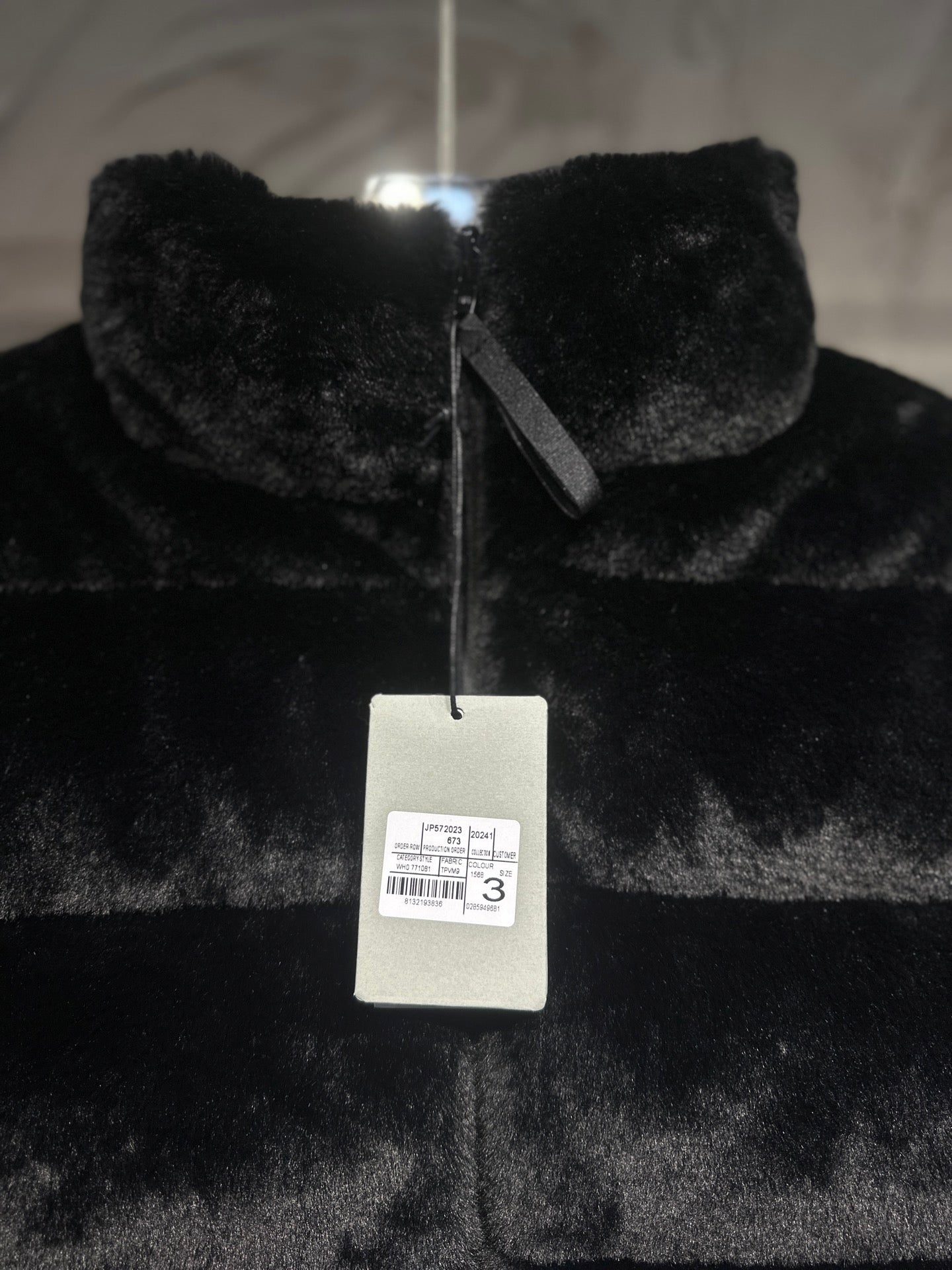 Black faux-fur puffer vest with front zipper and hanging label.