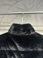 Black faux-fur puffer vest close-up of raised collar and top panel.