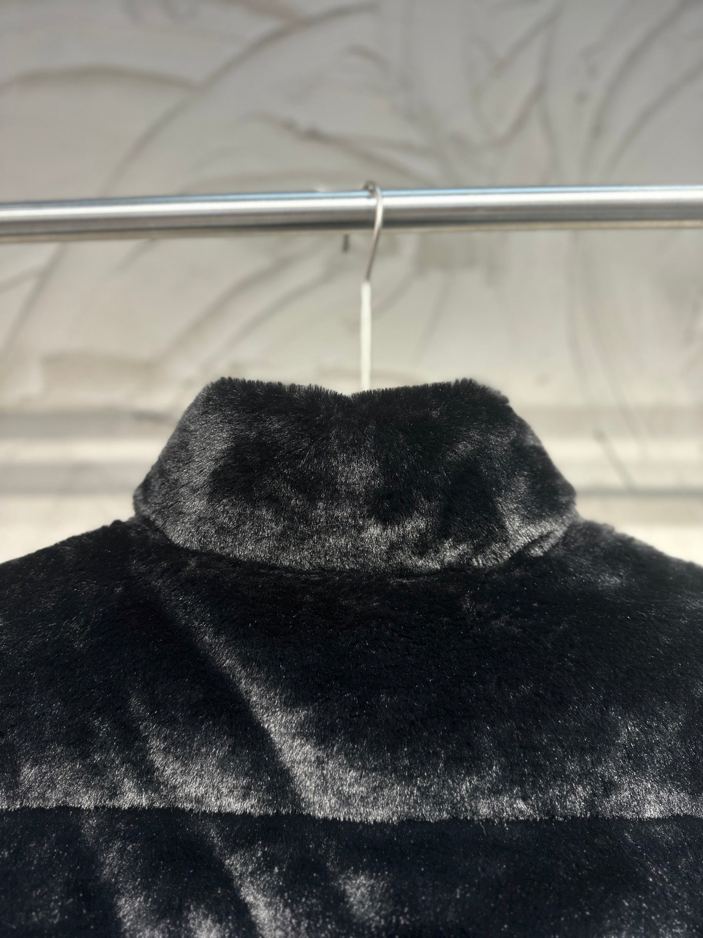 Black faux-fur puffer vest close-up of raised collar and top panel.