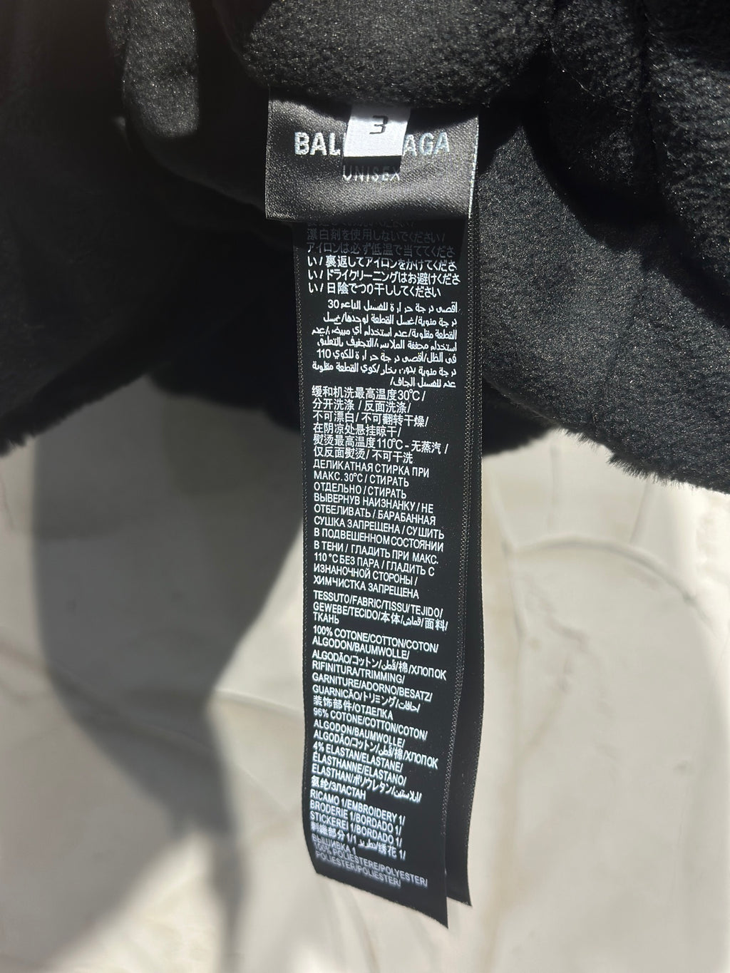 Black garment neck label reading BALENCIAGA with care instructions