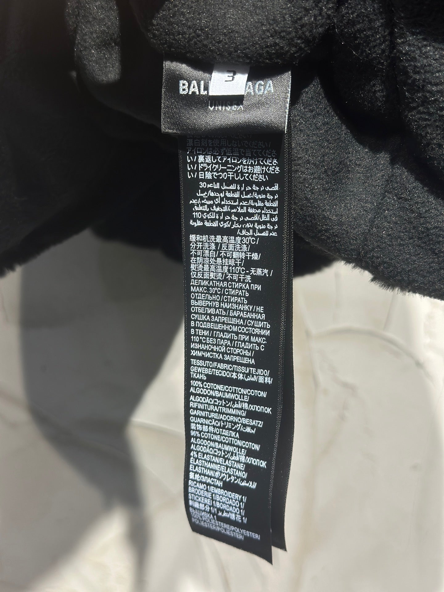 Black garment neck label reading BALENCIAGA with care instructions