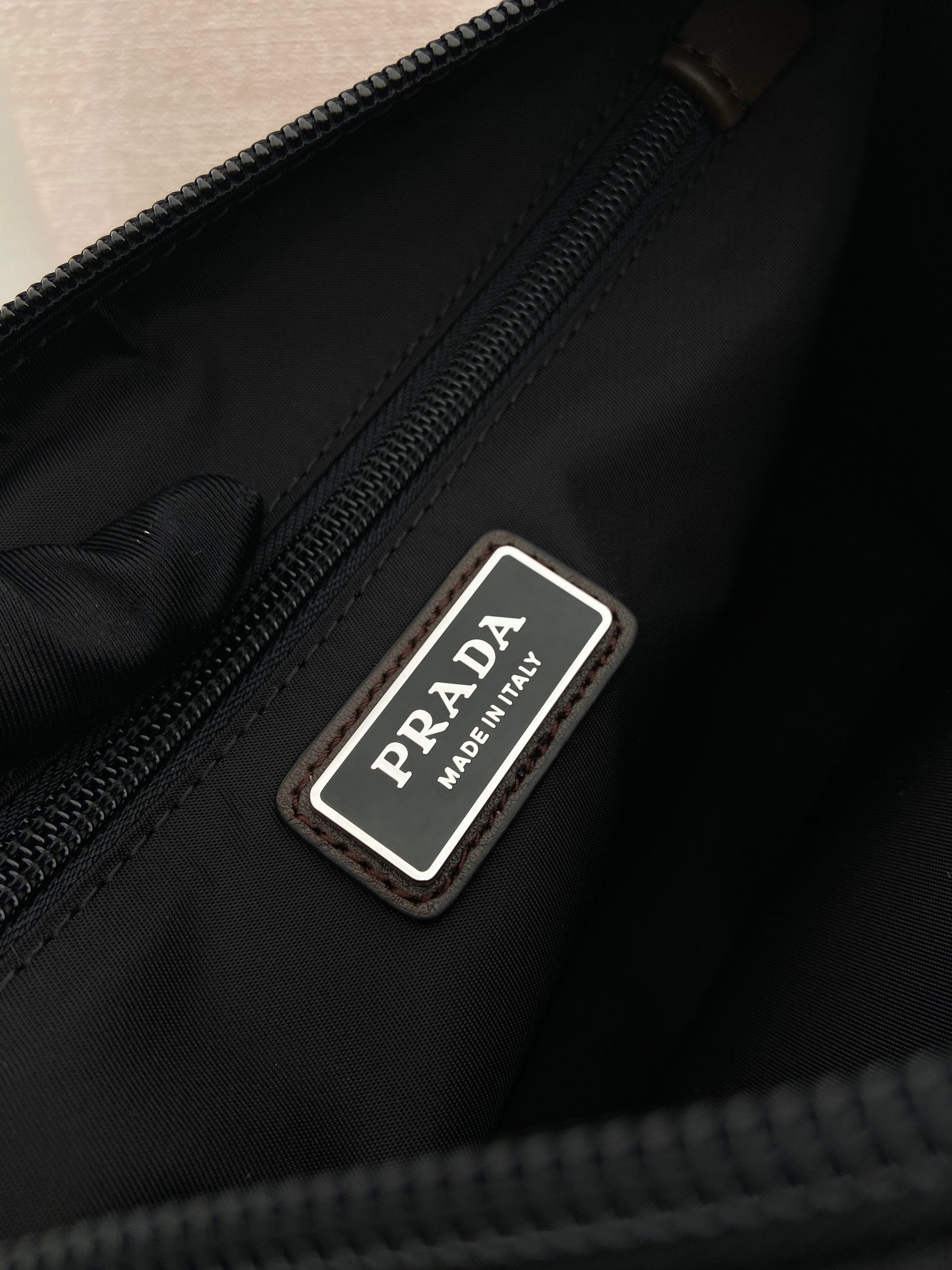 Prada nylon bag with stitched PRADA logo label near zipper