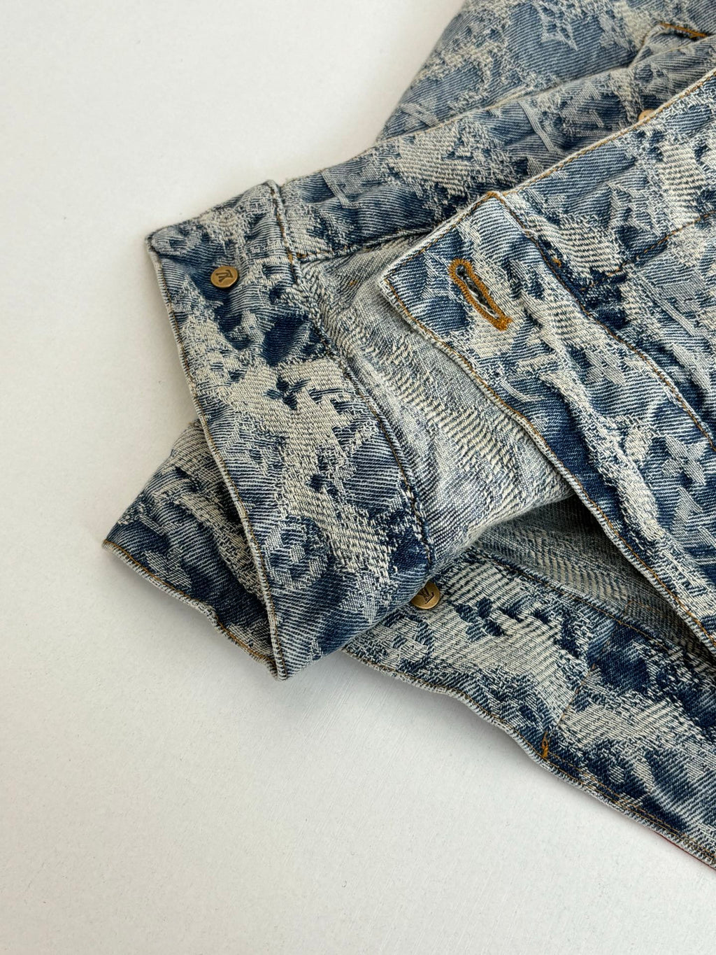 Close-up of blue denim pants waistband and front button with gold hardware