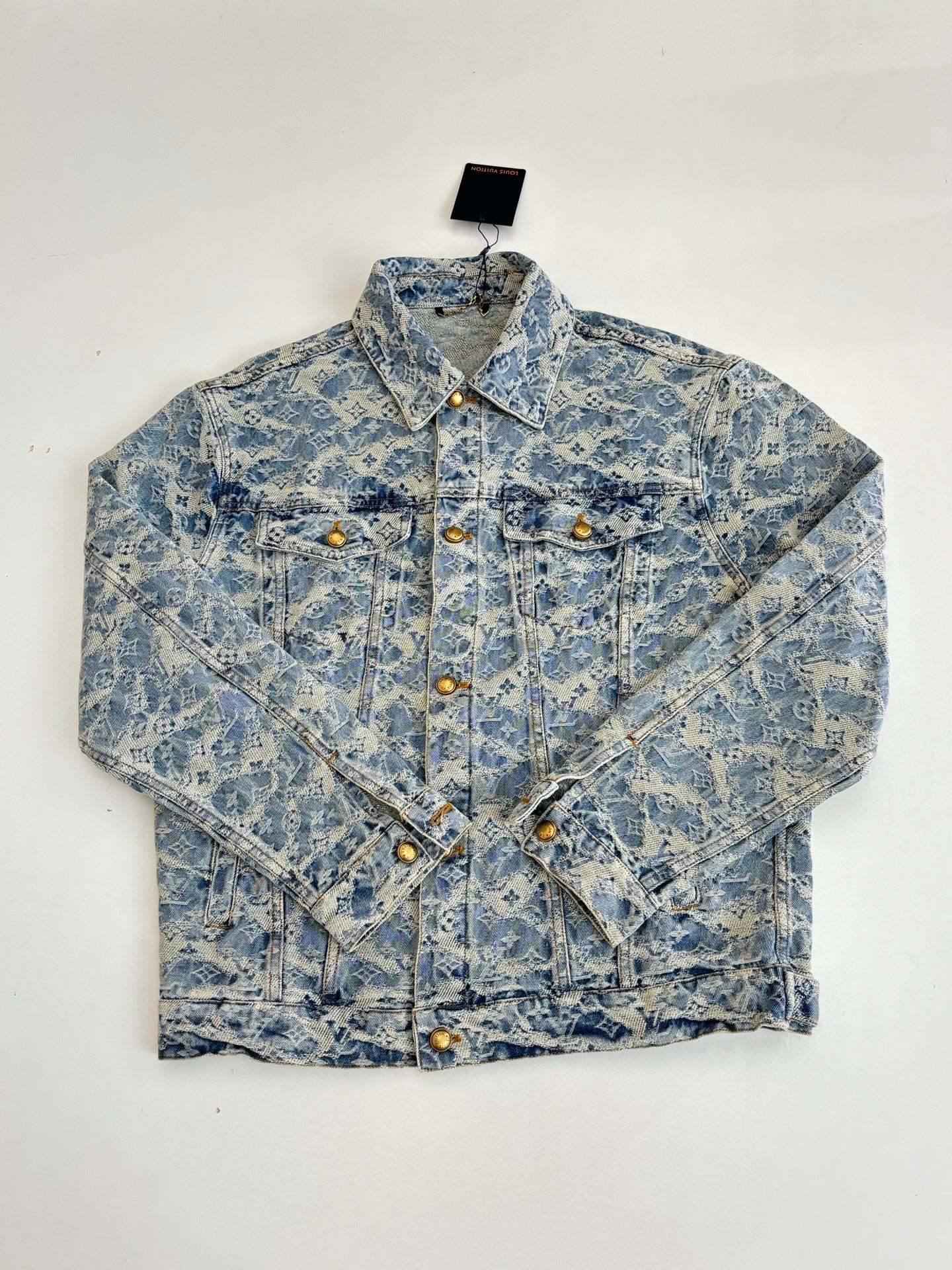 Blue denim jacket front view with allover monogram pattern, gold buttons, pointed collar