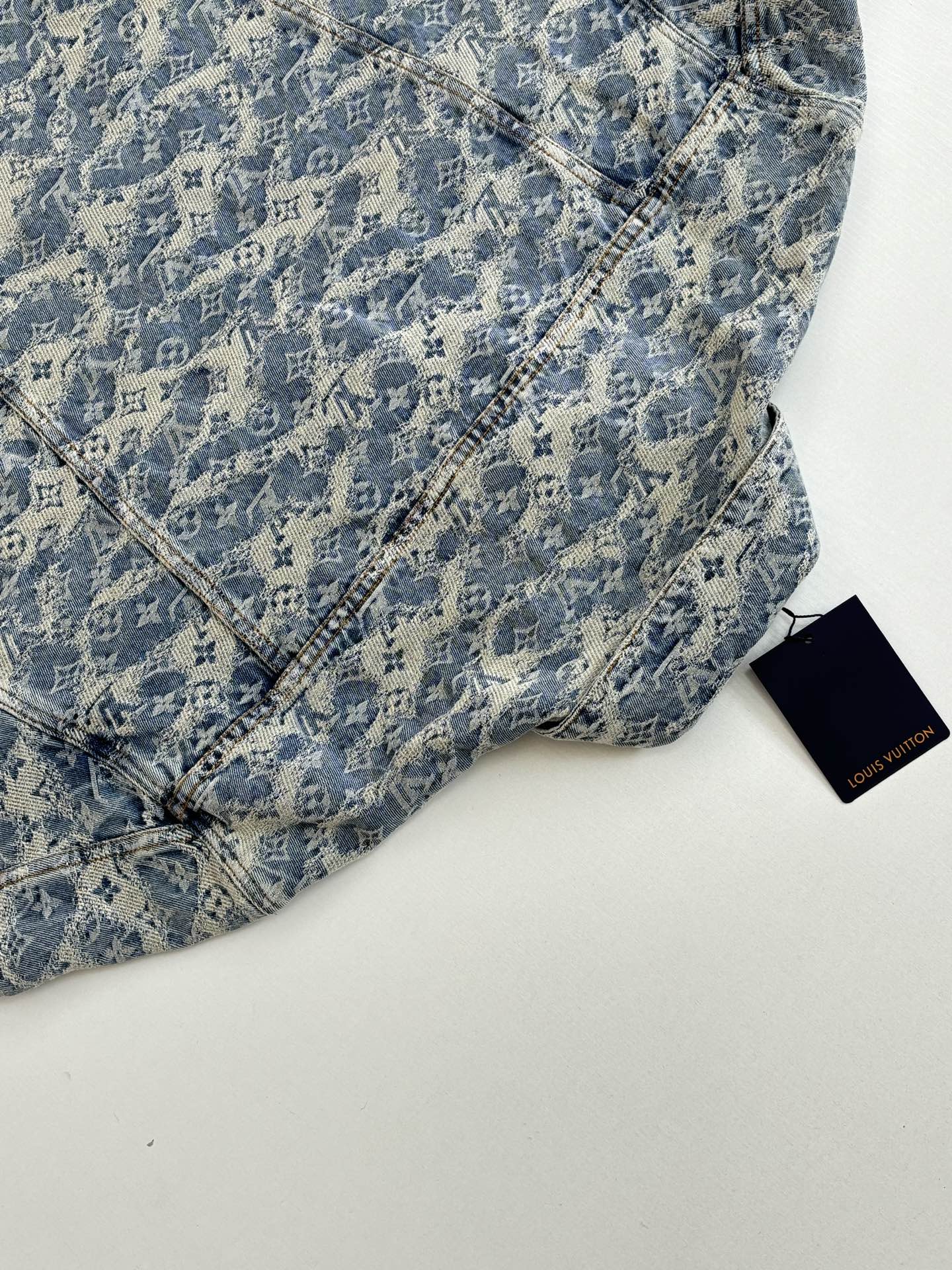 Blue monogram denim garment with diagonal seam stitching and Louis Vuitton tag