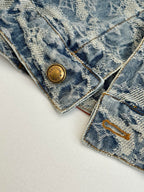 Close-up of blue denim monogram collar area with gold button and contrast stitching