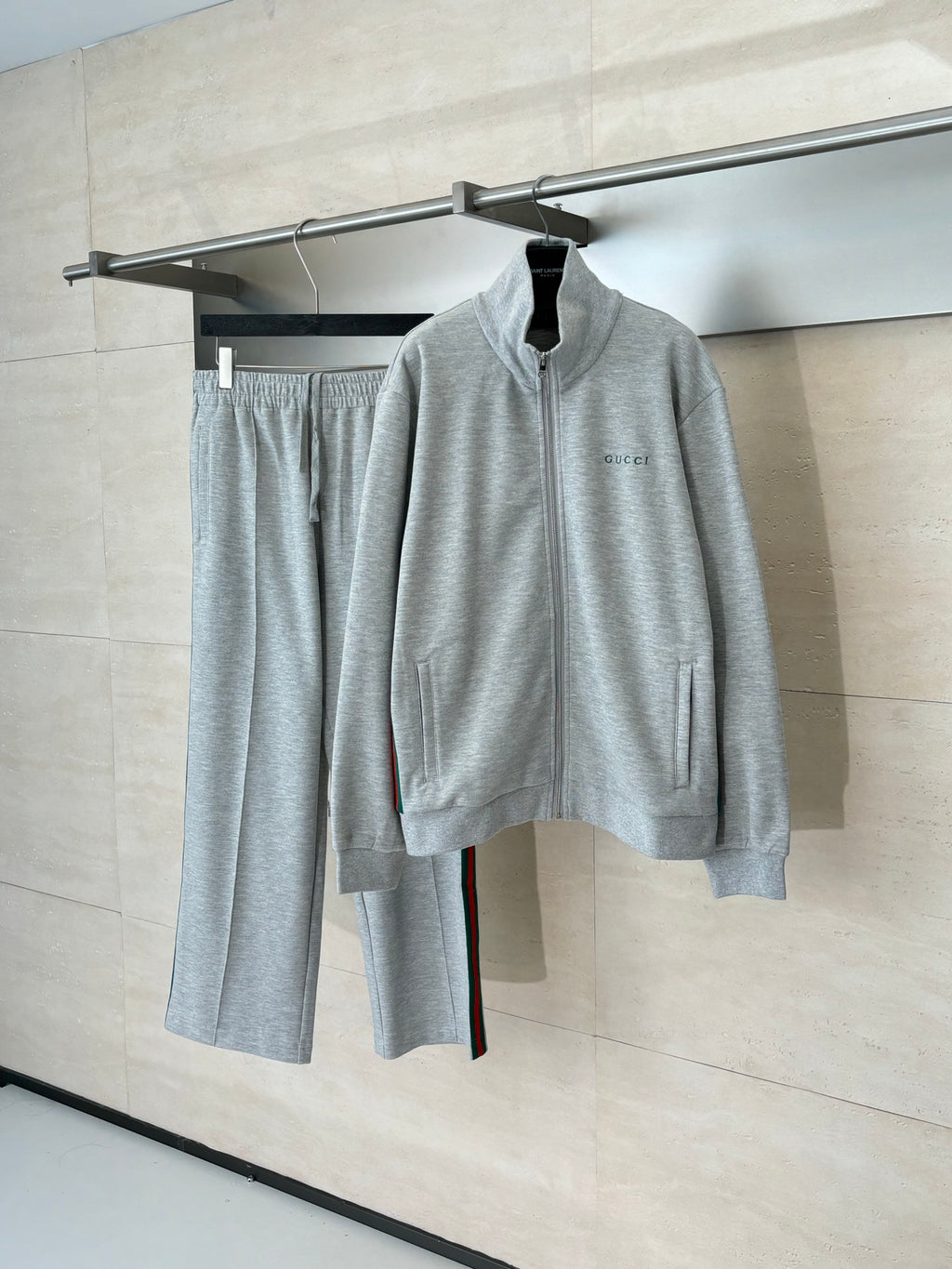 Grey Gucci zip-up jacket and matching pants set on hangers