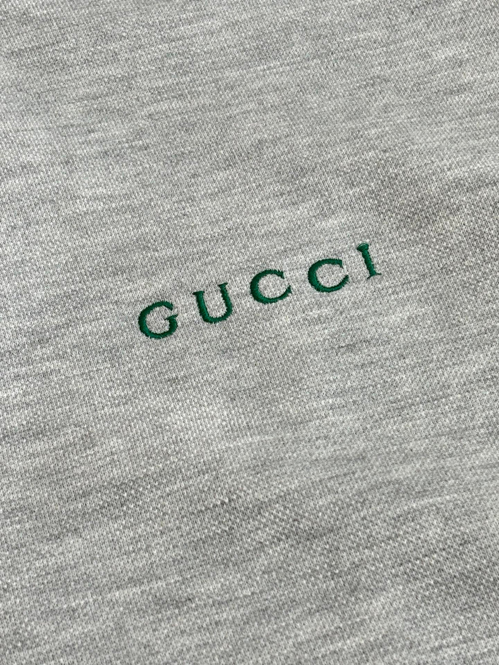 Grey fabric close-up with green Gucci logo text