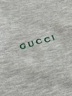 Grey fabric close-up with green Gucci logo text