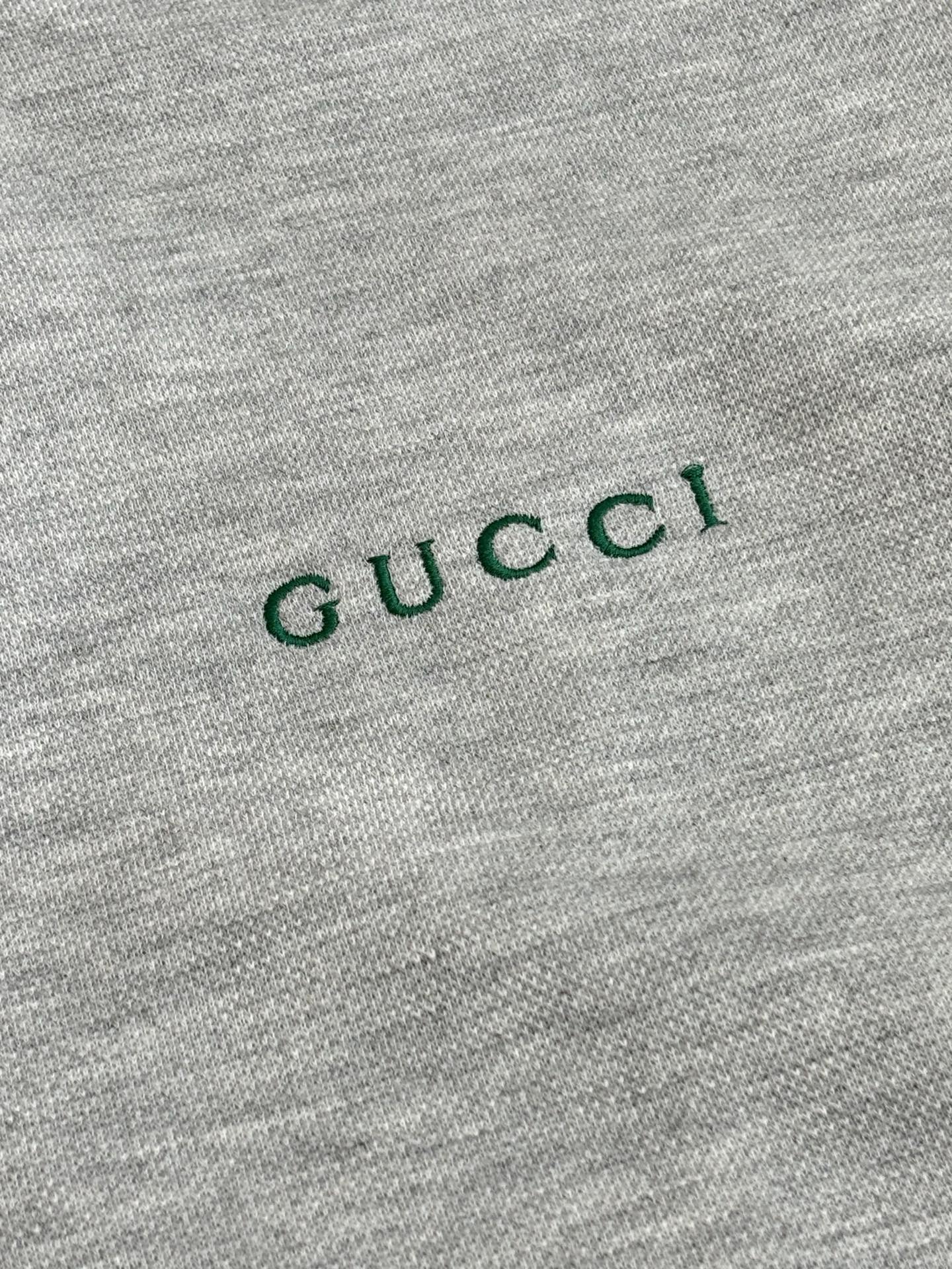 Grey fabric close-up with green Gucci logo text