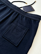 Dark navy drawstring pants with embossed monogram patch and pleated waistband