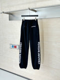 Black jogger pants with elastic cuffs and side graphic print, hanging on a hook