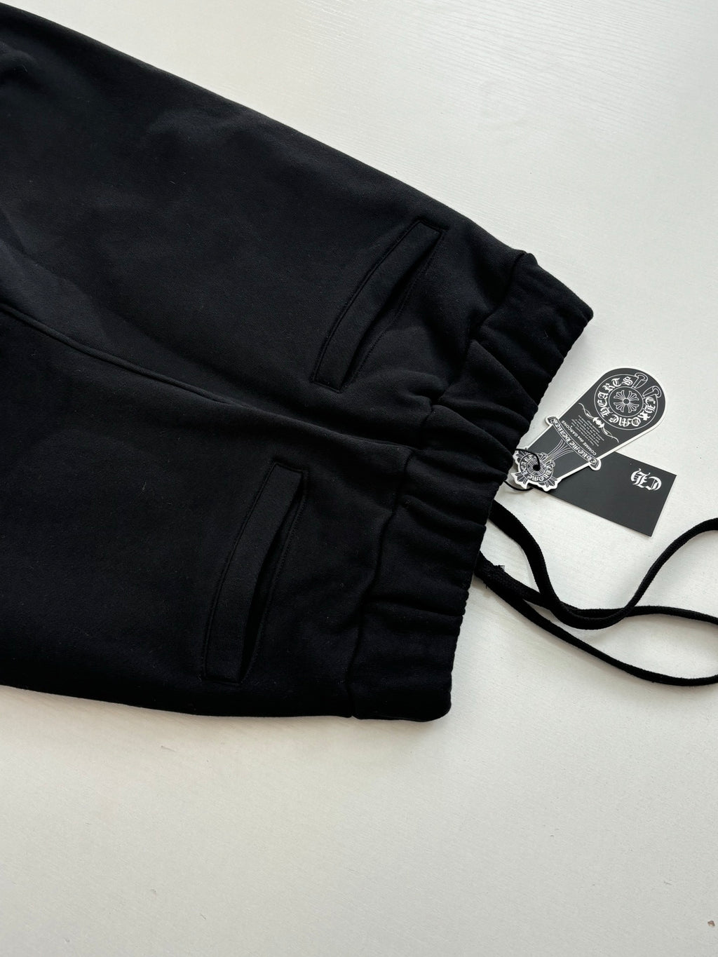 Black jogger pants with front pockets and drawstring, laid flat