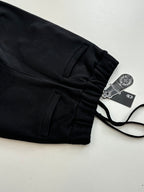 Black jogger pants with front pockets and drawstring, laid flat