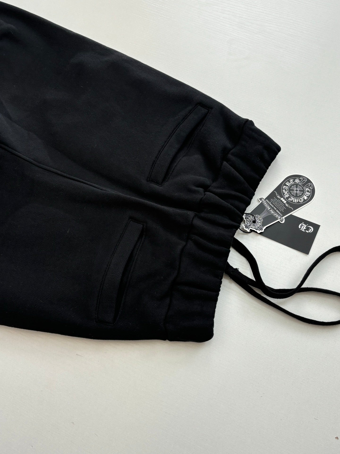 Black jogger pants with front pockets and drawstring, laid flat
