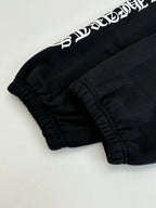 Black sweatpants cuff detail with elastic hem and white side graphic lettering.