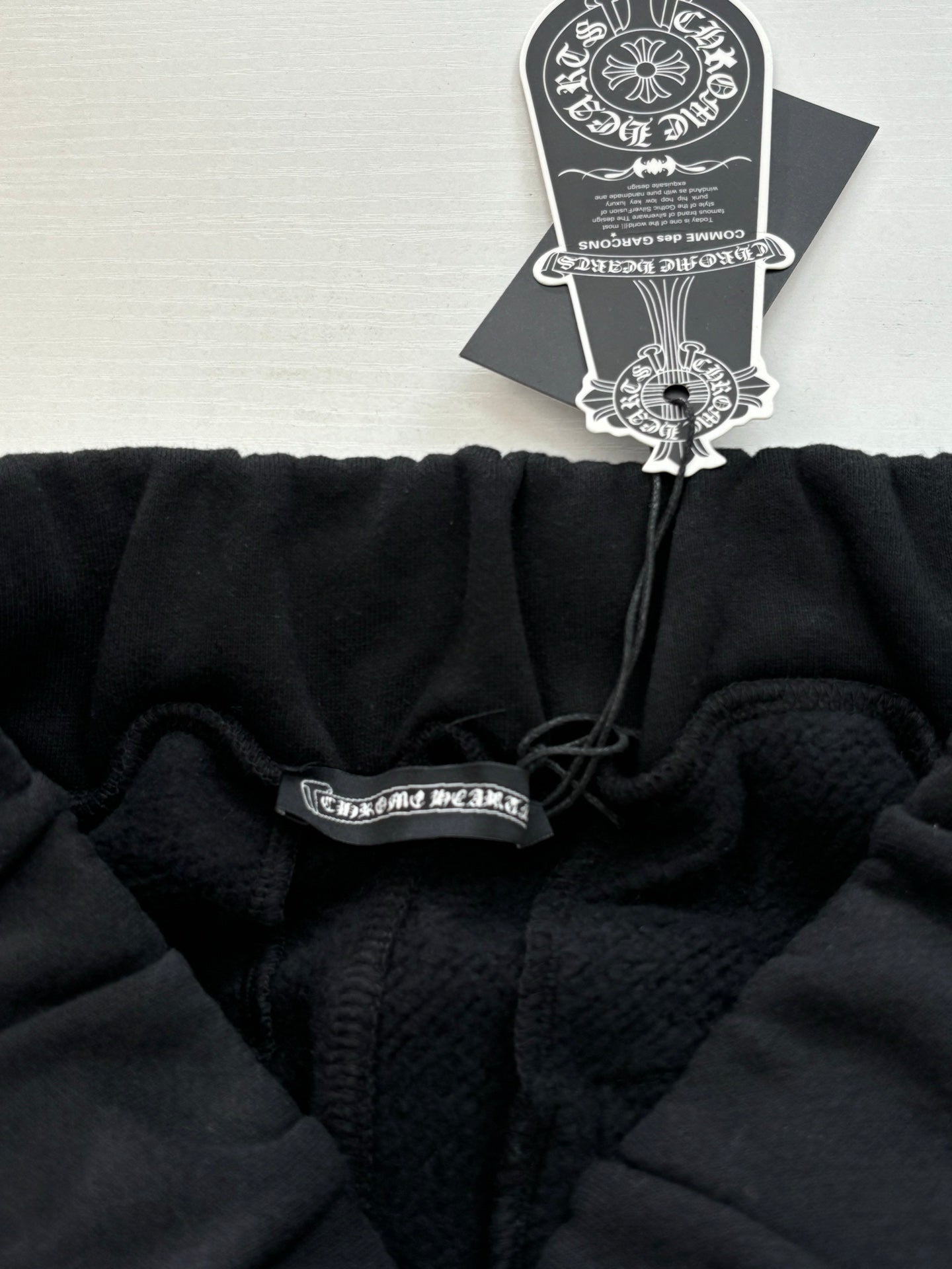 Black jogger pants with drawstring toggle and hang tag near elastic waistband