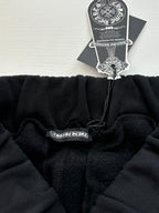 Black sweatpants waistband with drawstring and hanging label tag, gathered cuff.