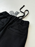 Black sweatpants waistband and front pocket with hanging brand tag on drawstring.