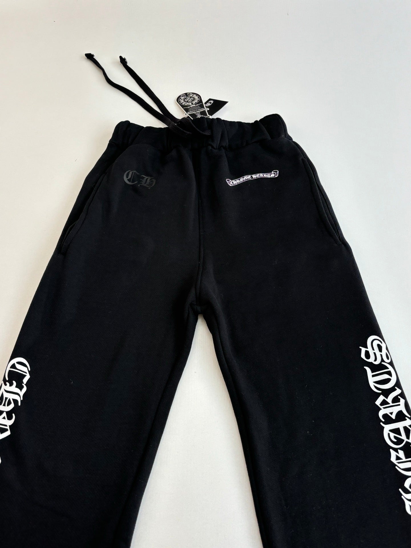 Black sweatpants, elastic waistband with drawstring and side graphic logos.
