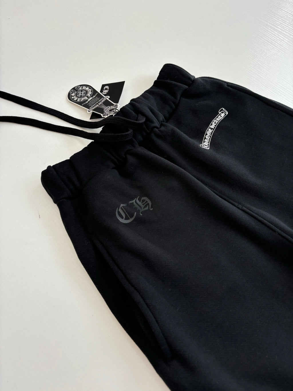 Black jogger pants with small front logo patch and drawstring detail
