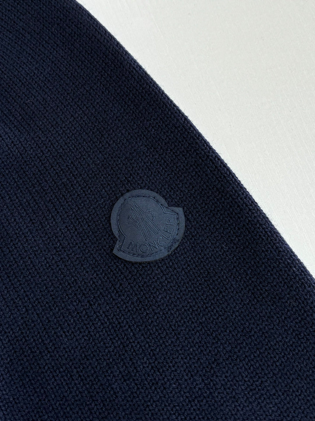 Navy knit sweater with embossed circular logo patch on the sleeve