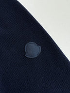 Navy knit sweater with embossed circular logo patch on the sleeve
