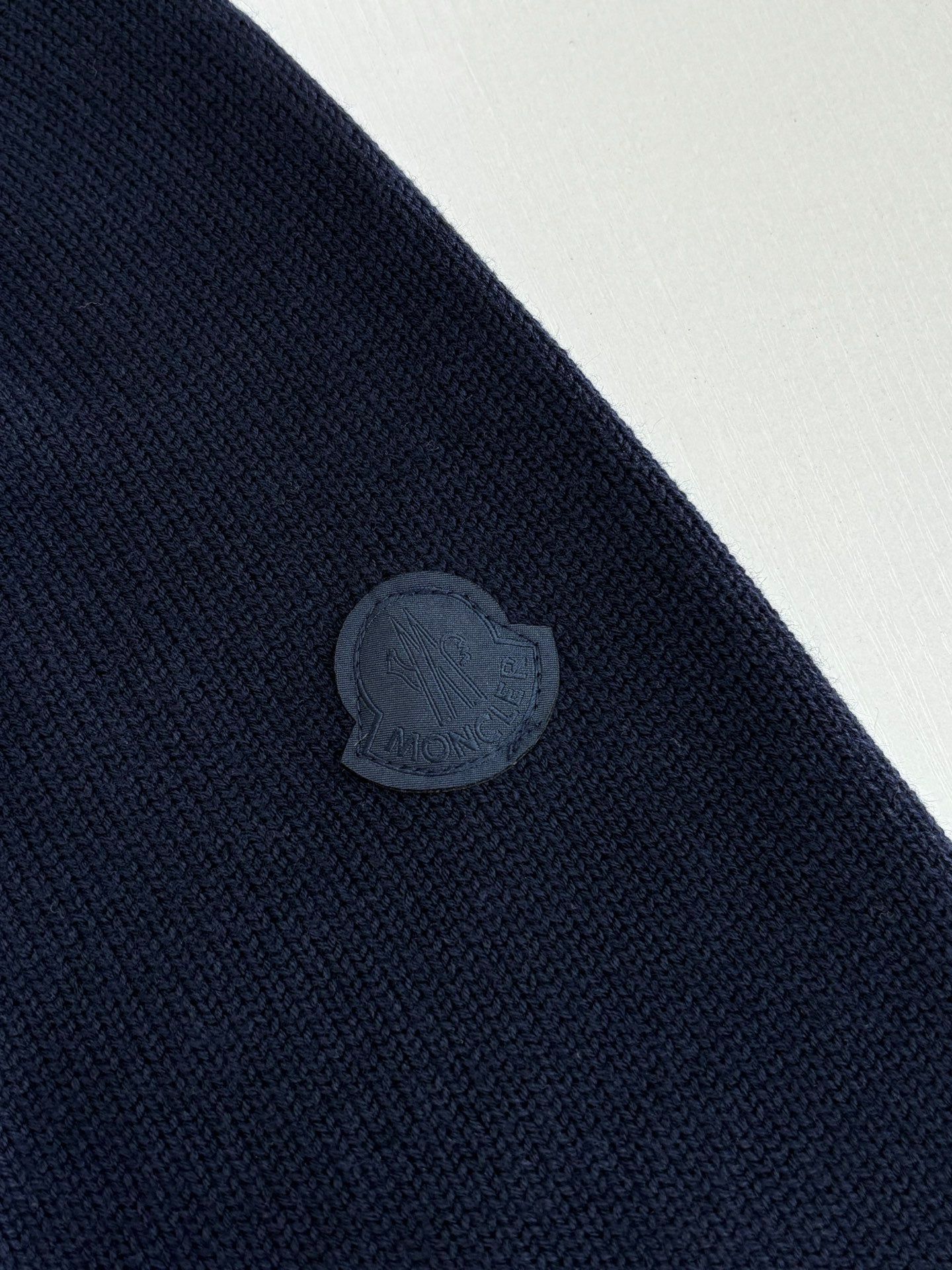 Navy knit sweater with embossed circular logo patch on the sleeve