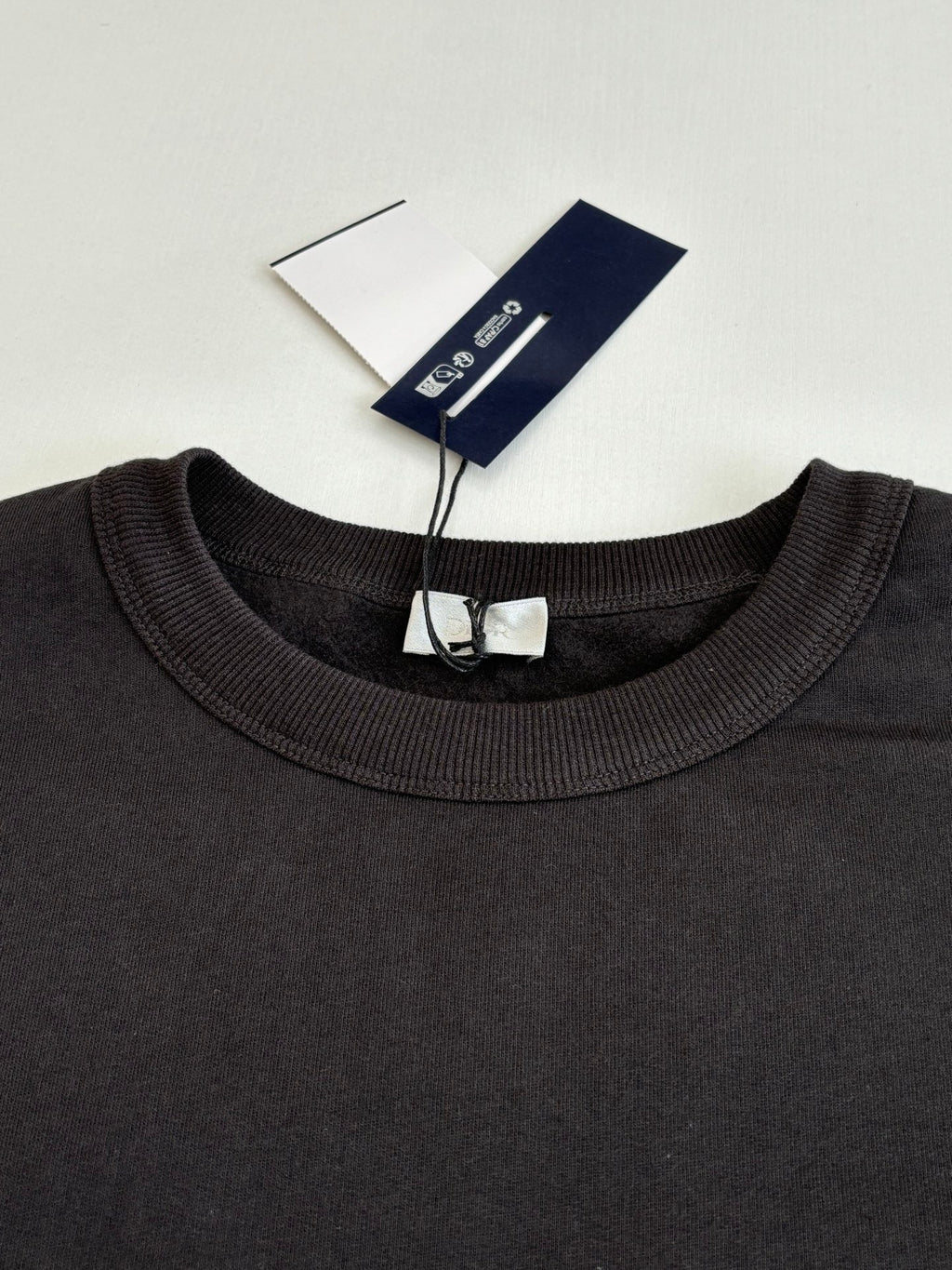 Dark crewneck sweatshirt close-up with ribbed neckline and tag