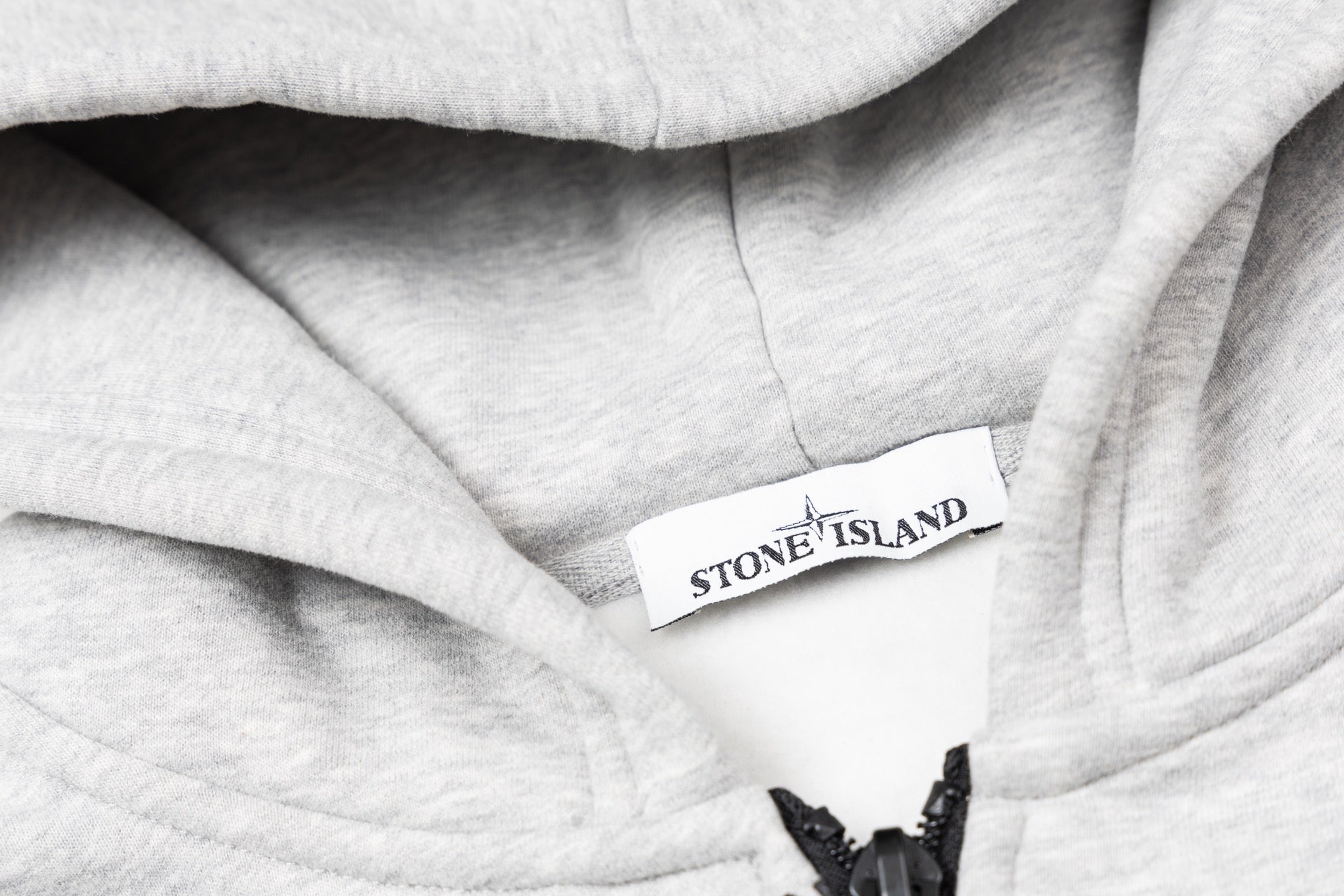 Heather gray hoodie interior label on hood lining with black drawcord ends