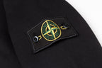 Black zip-up hoodie front patch with yellow-green circular emblem on stitched label