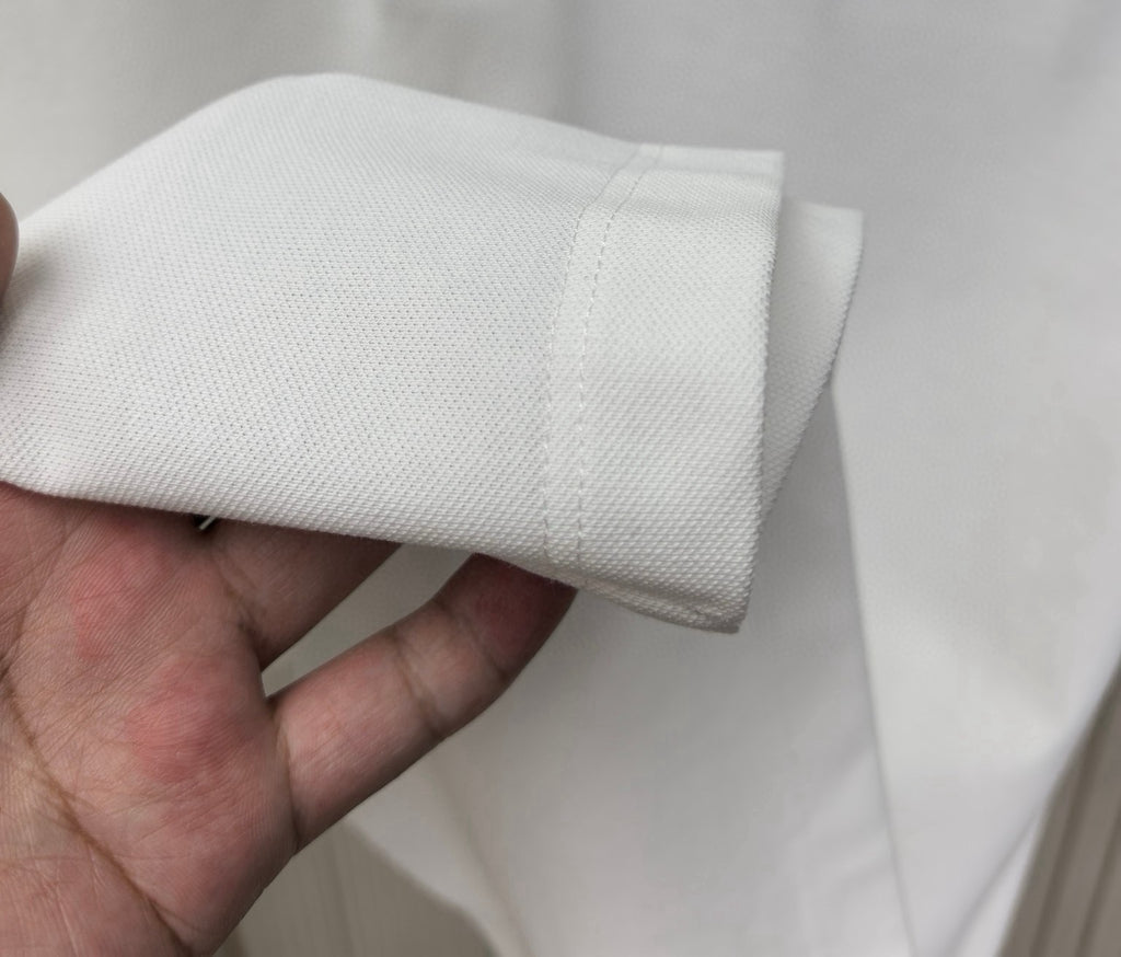 White polo shirt sleeve cuff with stitched seam and ribbed edge