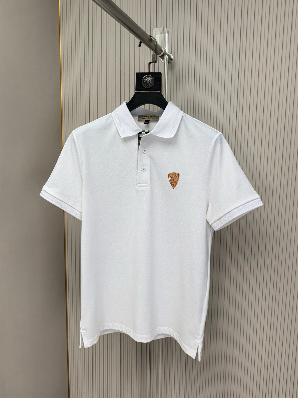 White polo shirt with pointed collar and button placket, small chest emblem logo