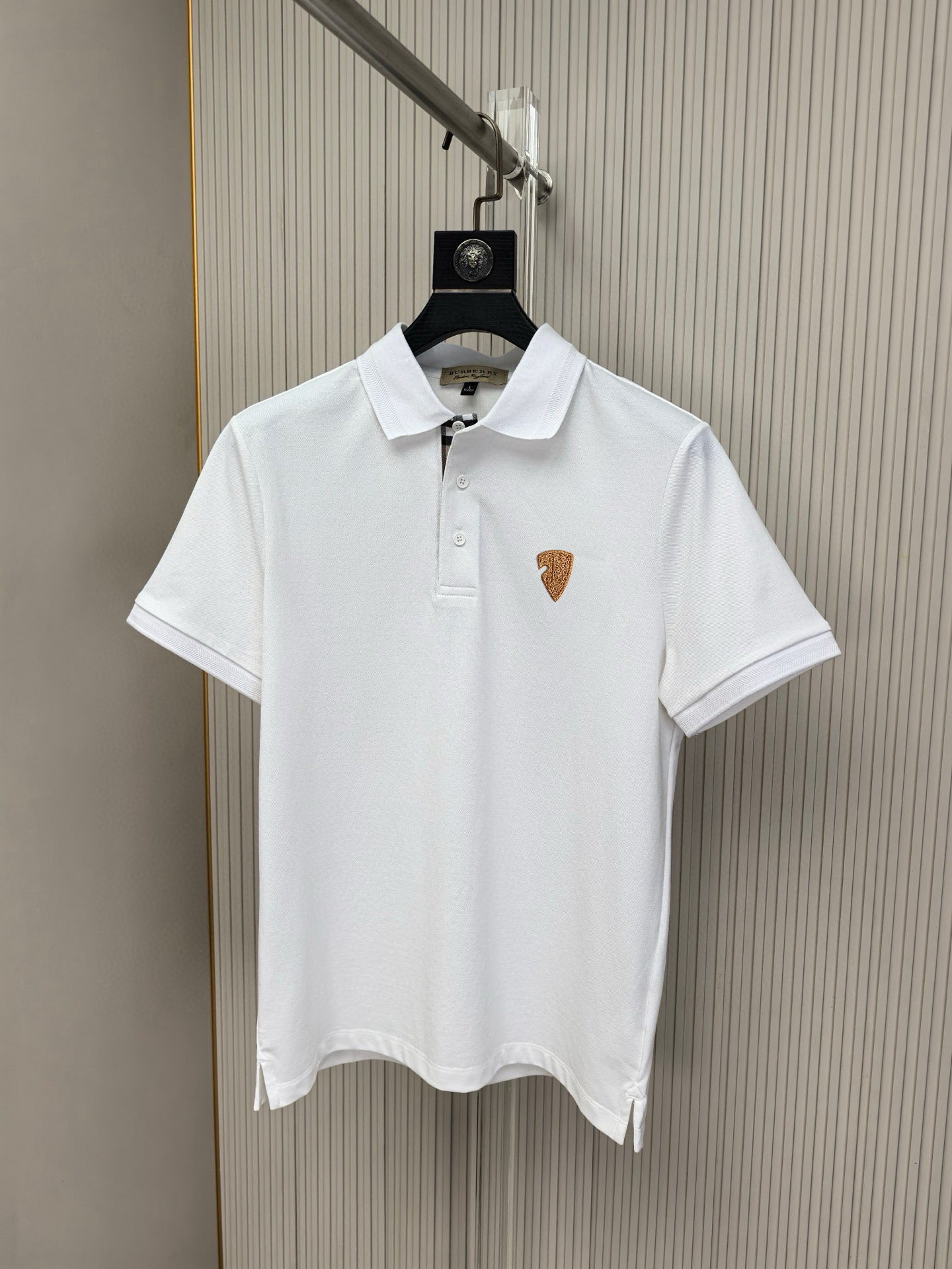 White polo shirt with pointed collar and button placket, small chest emblem logo