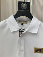 White polo shirt with point collar, buttons, and Burberry London England chest logo patch