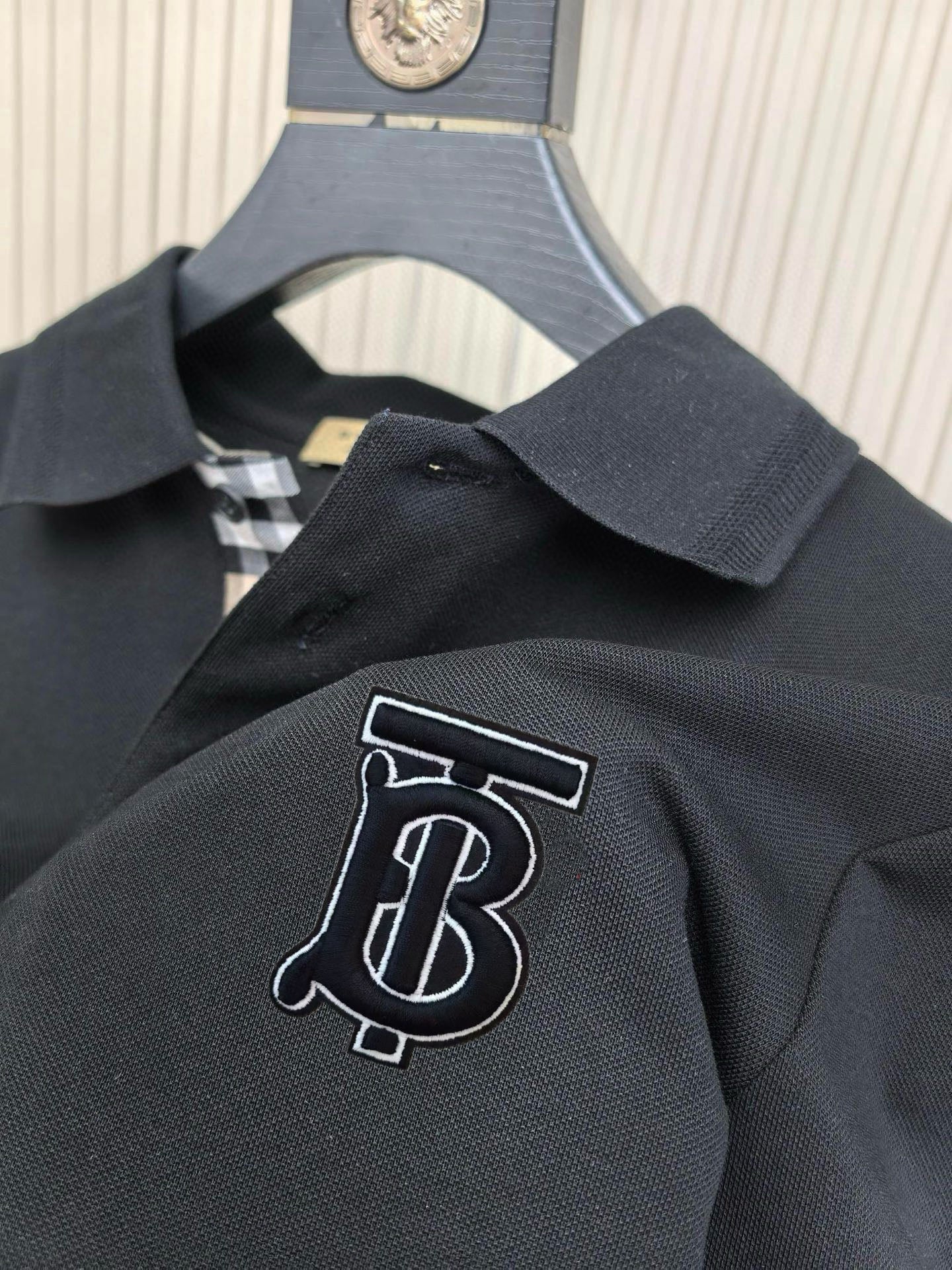 Burberry polo shirt chest monogram patch on dark navy fabric; soft collar detail.