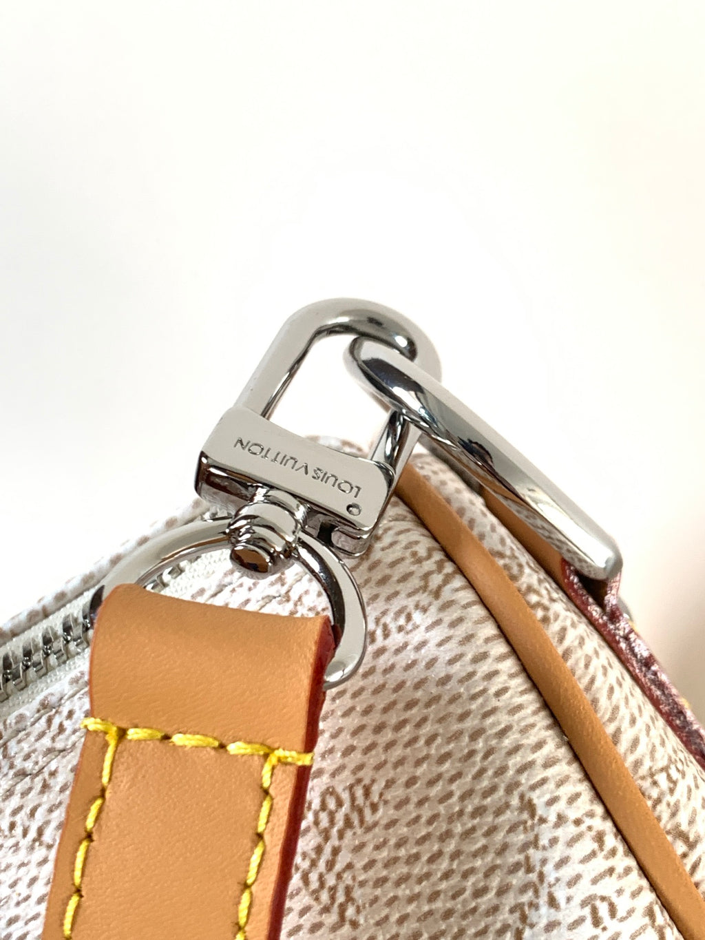 Louis Vuitton bag hardware with silver clasp and tan leather strap on textured lining