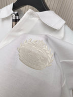 White polo shirt fabric close-up with large embroidered crest on chest