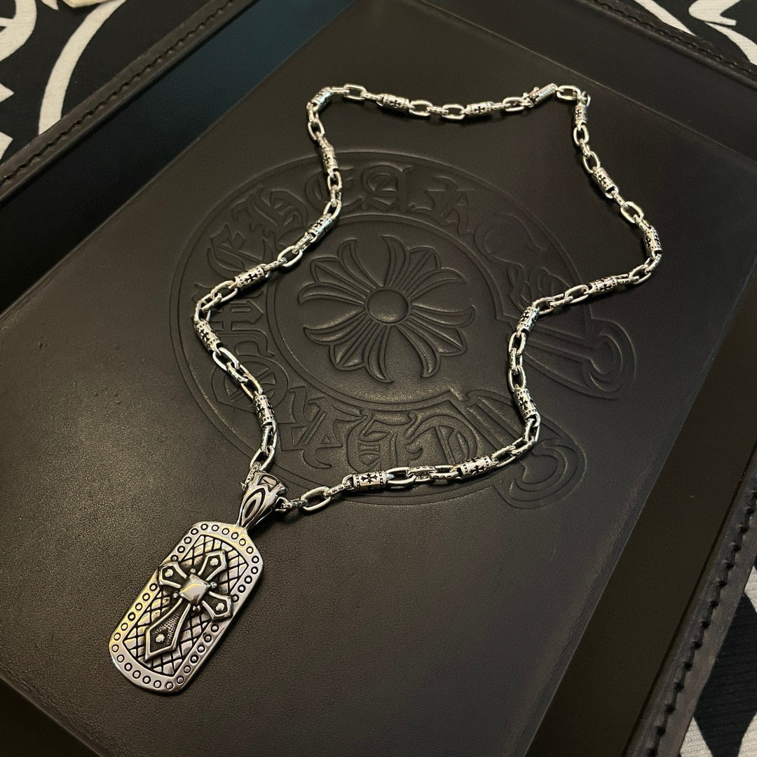 Silver-tone chain necklace with rectangular pendant on dark display pouch