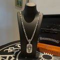 Silver-tone chain necklace with rectangular pendant on black display bust