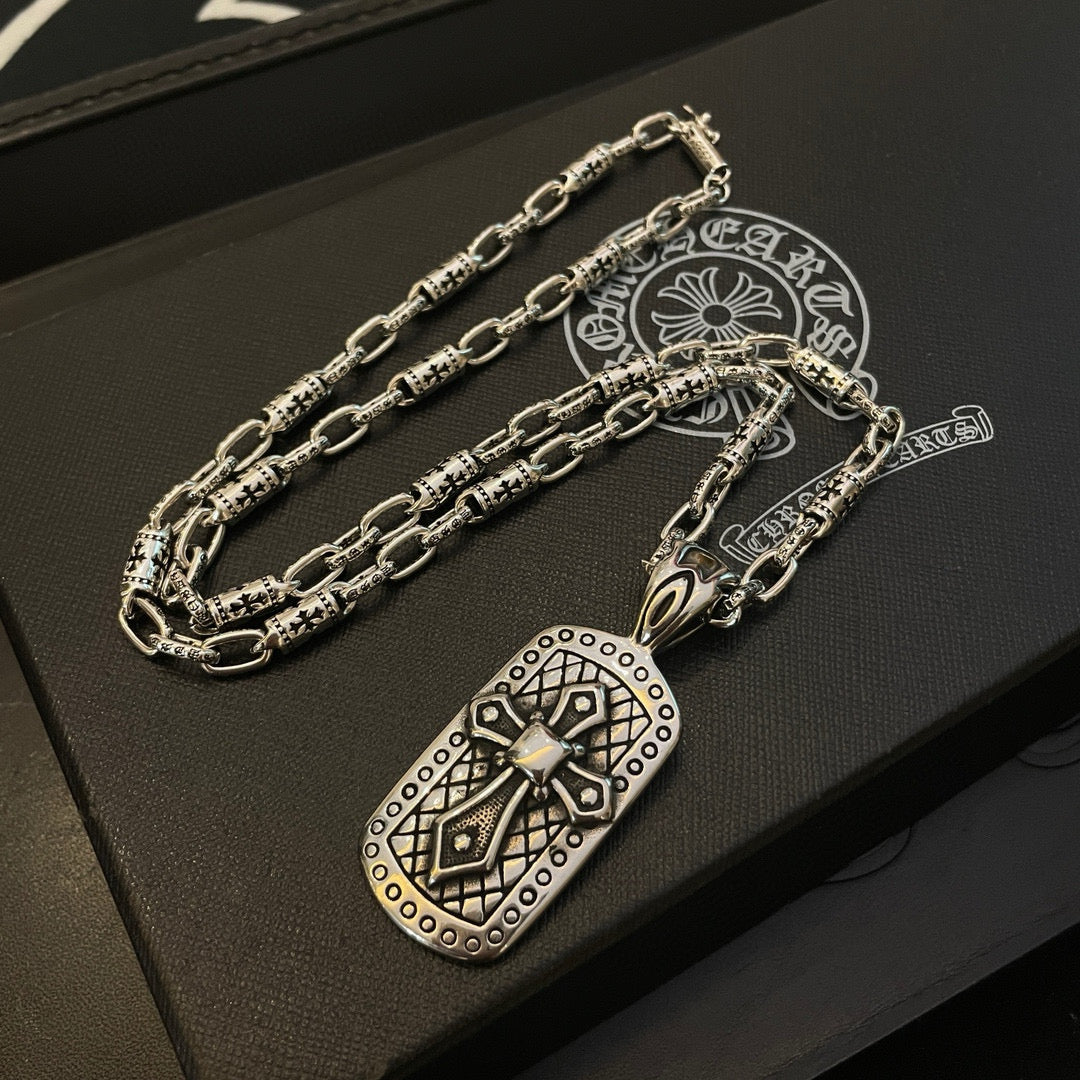 Silver-tone chain necklace with rectangular pendant on a jewelry box with clasp visible.