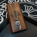 Silver-tone chain necklace with rectangular pendant hanging on a wooden display stand.