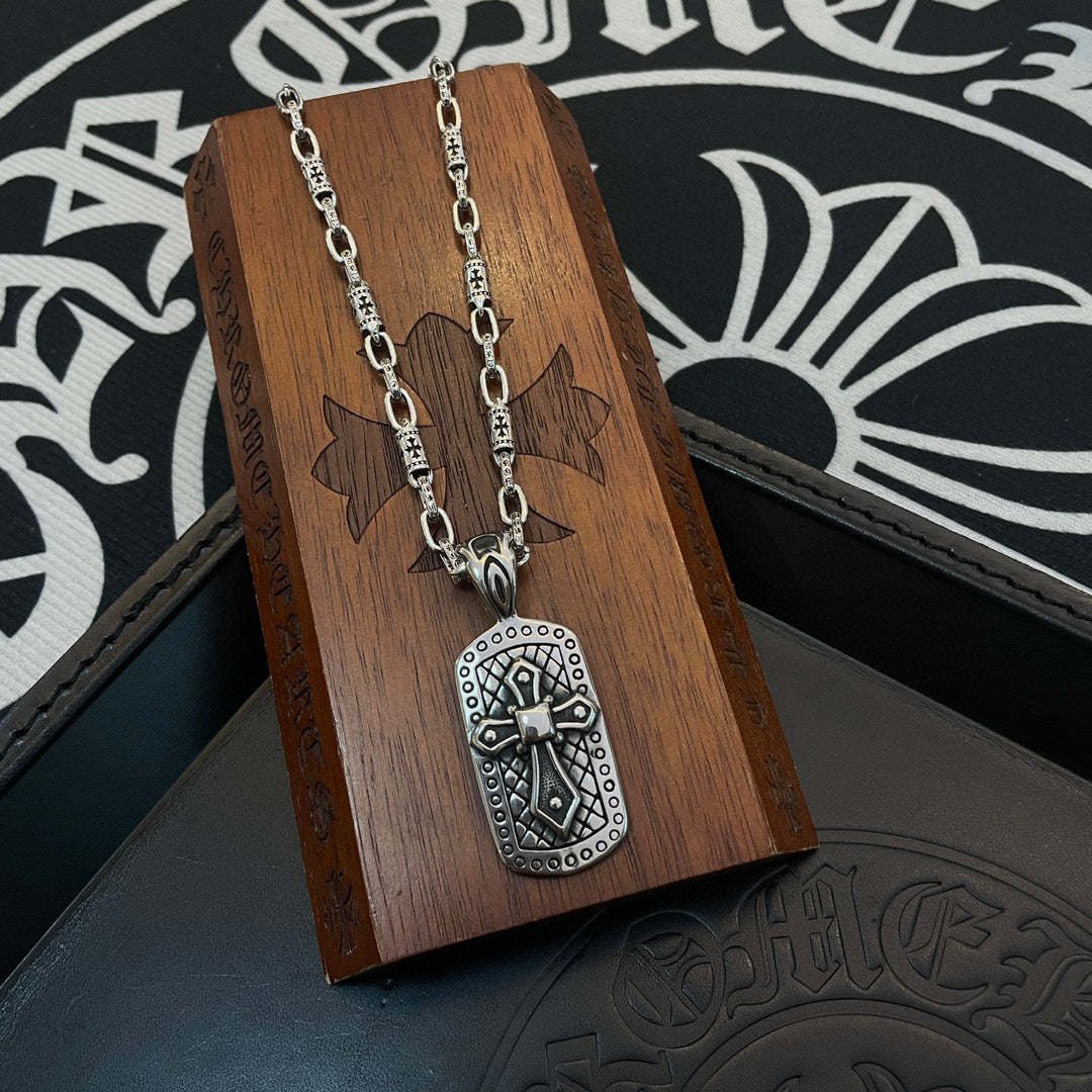 Silver-tone chain necklace with rectangular pendant hanging on a wooden display stand.