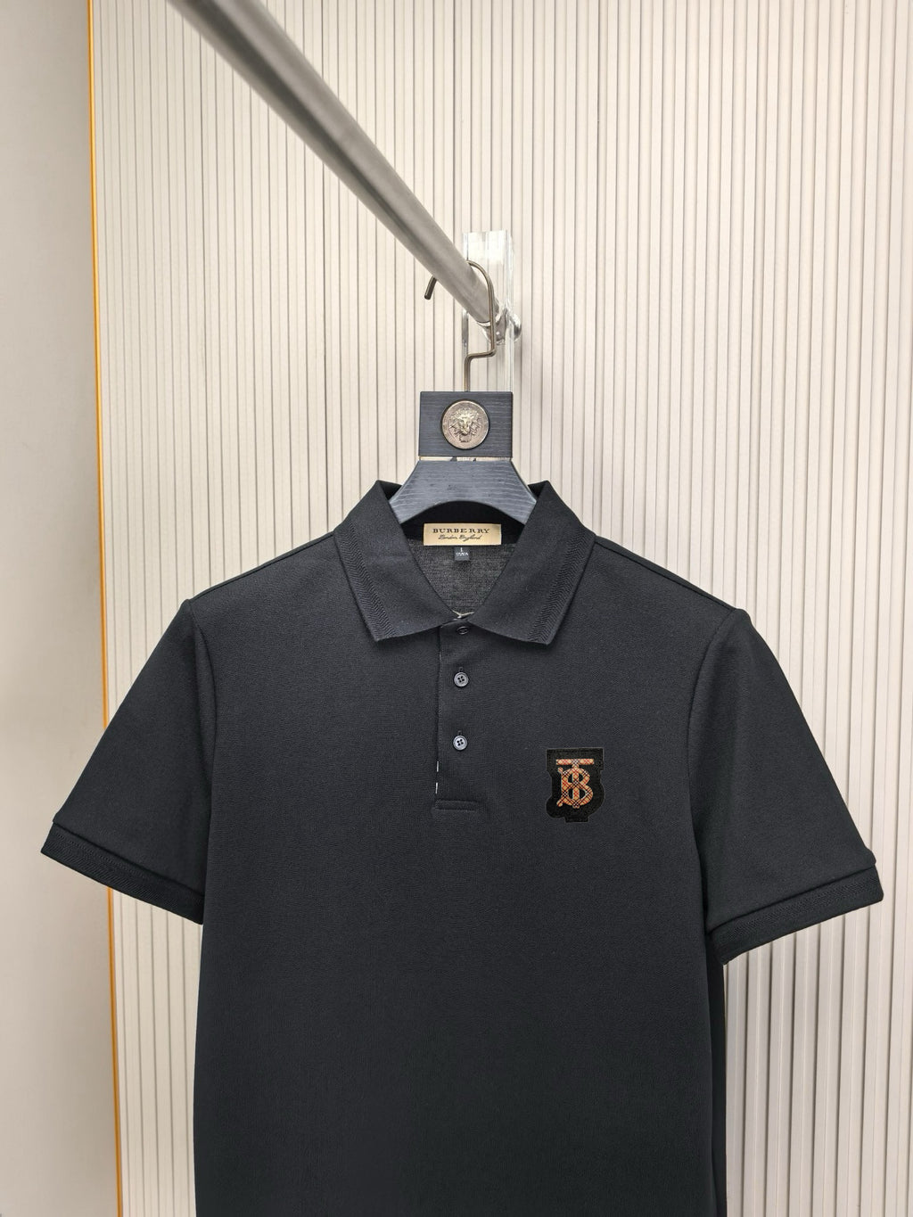 Black polo shirt on hanger with Burberry monogram logo at chest