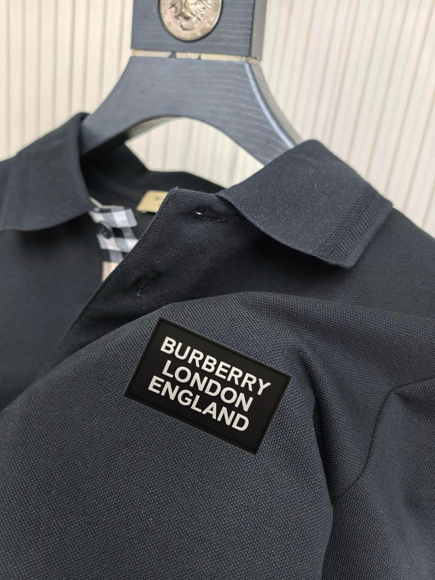 Burberry polo shirt neck label patch on dark fabric, with checked inner trim