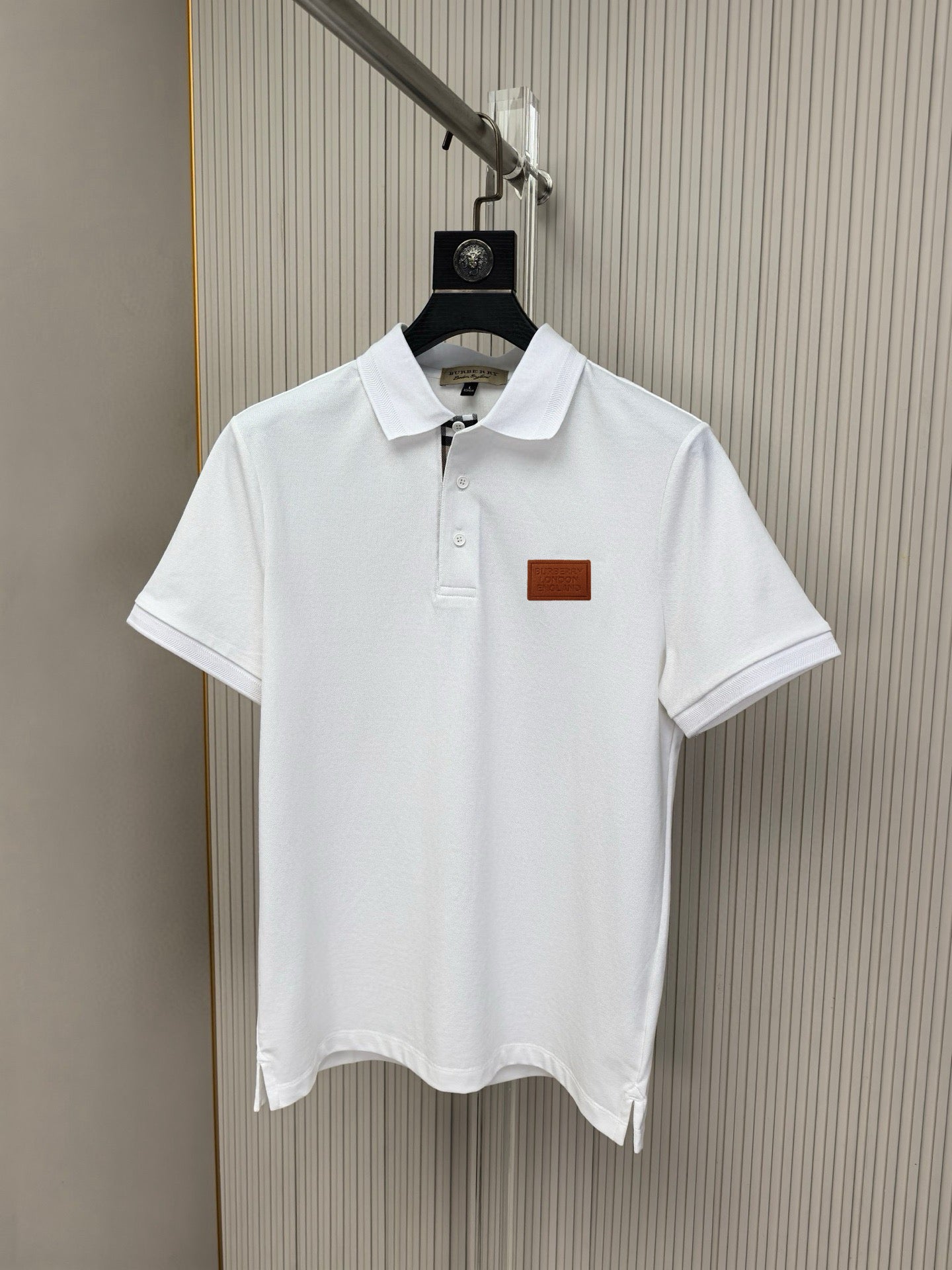 White short-sleeve polo shirt on hanger, button placket and chest logo patch