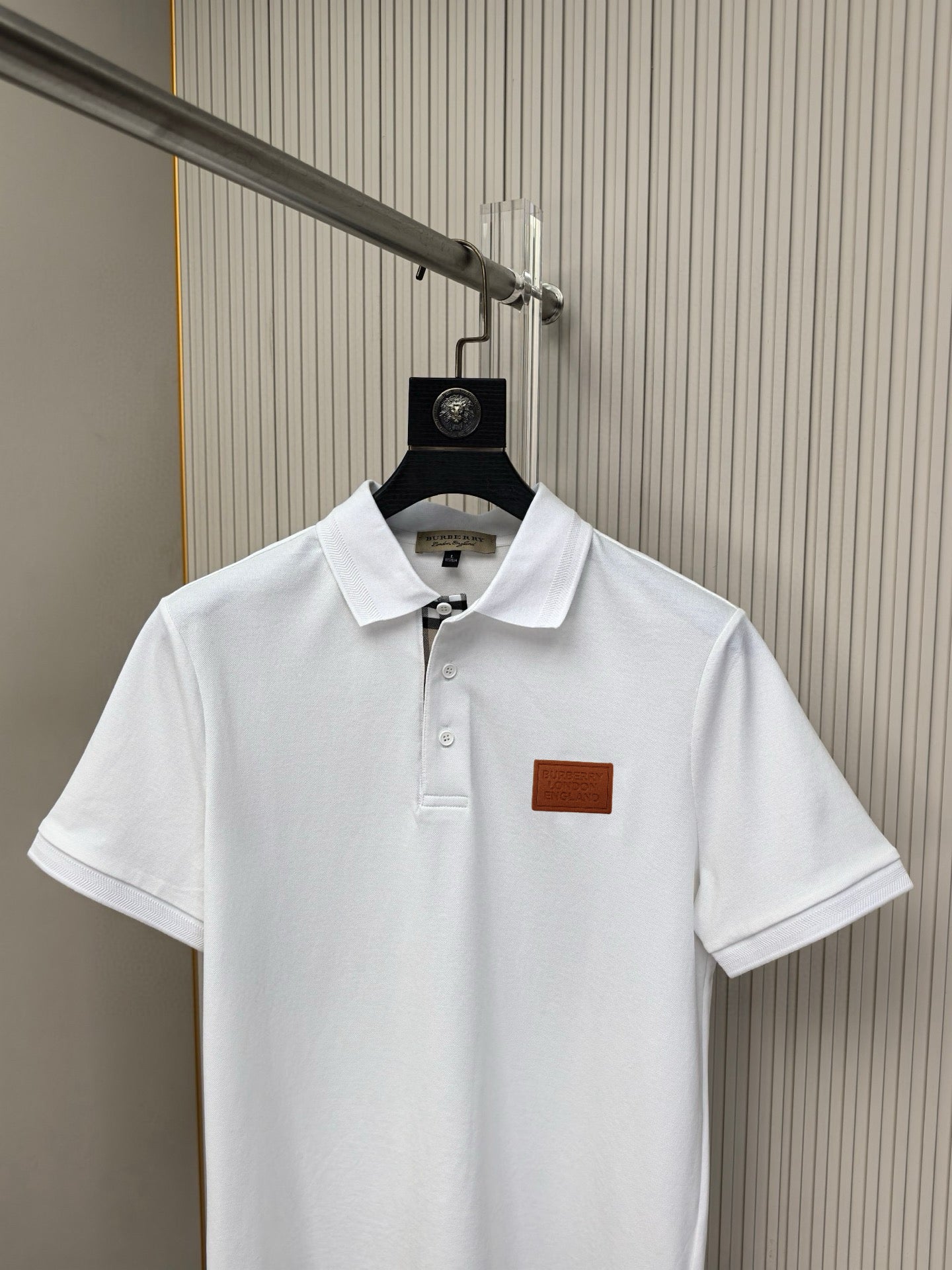 White polo shirt on hanger, short sleeves and chest logo patch